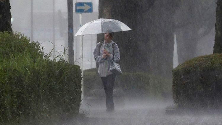 Ilustrasi. Seorang warga berjalan kaki ditengah hujan lebat di Kirishima, Prefektur Kagoshima. (Foto: Reuters)