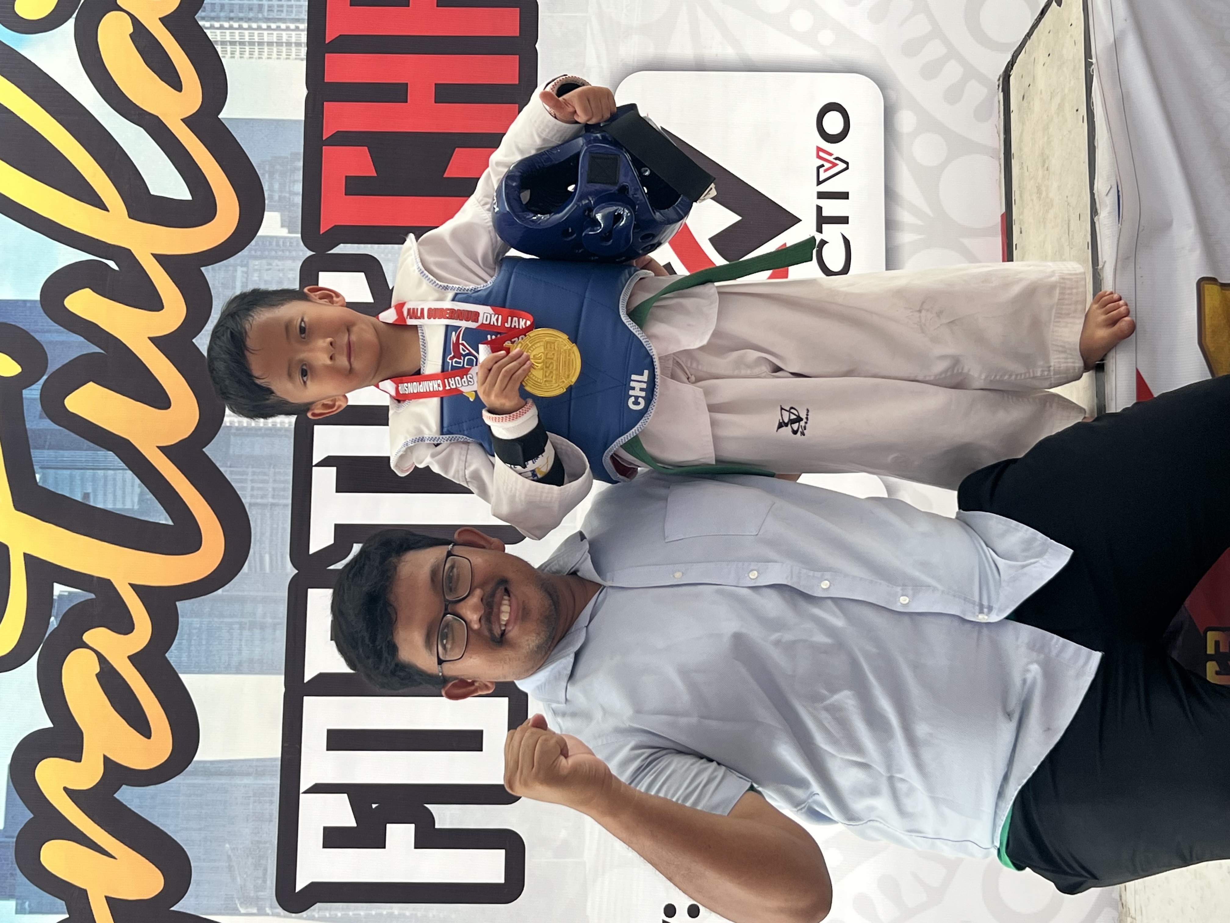 Armstrong Daud Abisantha (7) dari Rugaza Taekwondo Club yang berhasil meraih juara 1 medali emas kategori Kyorugi Pemula Pra Cadet di turnamen Taekwondo Indonesia Student Sport Championship (ISSC) 3 Piala Gubernur DKI Jakarta 2025 berfoto bersama pelatihn