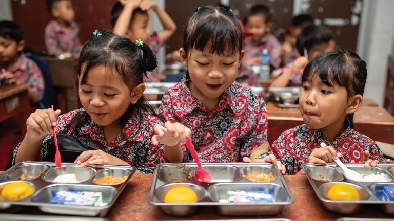 Ilustrasi anak-anak sekolah dasar tengah menikmati menu Makan Bergizi Gratis (MBG). Berdasarkan hasil Rakortas virtual bersama Presiden Prabowo Subianto, penyaluran MBG akan dilakukan selama lima hari sekolah kecuali di daerah 3T. (Foto: Istimewa)