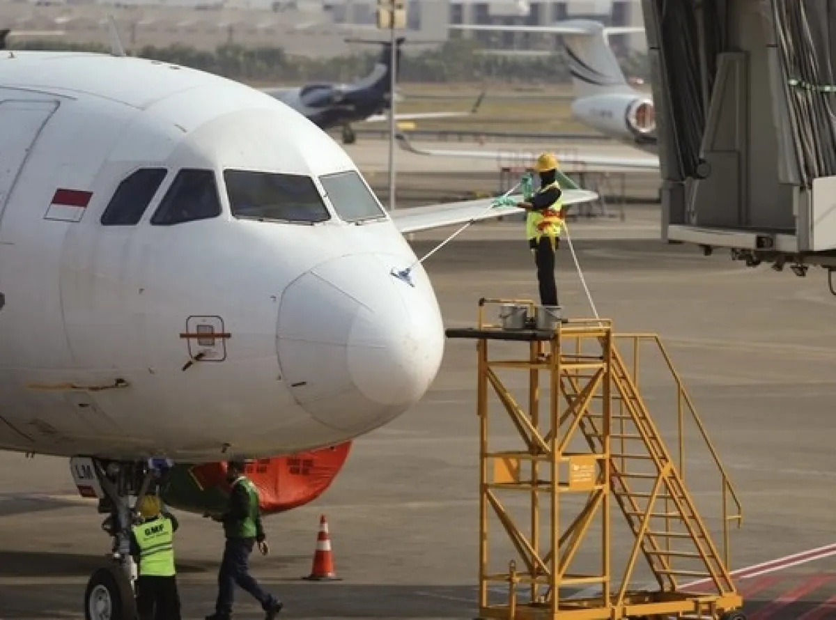 Tampak petugas kebersihan bandara tengah membersihkan badan pesawat yang dipenuhi debu abu vulkanik. (dok Warta Lentera)