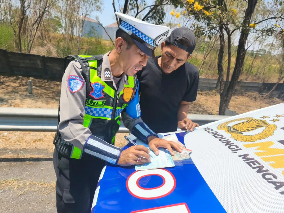 Seorang polisi lalulintas tengah menulis surat tilang kepada pengendara mobil yang seenaknya parkir di bahu jalan ruas tol Surabaya-Gempol. (Foto : Nice Aprily/Warta Lentera/JTT)